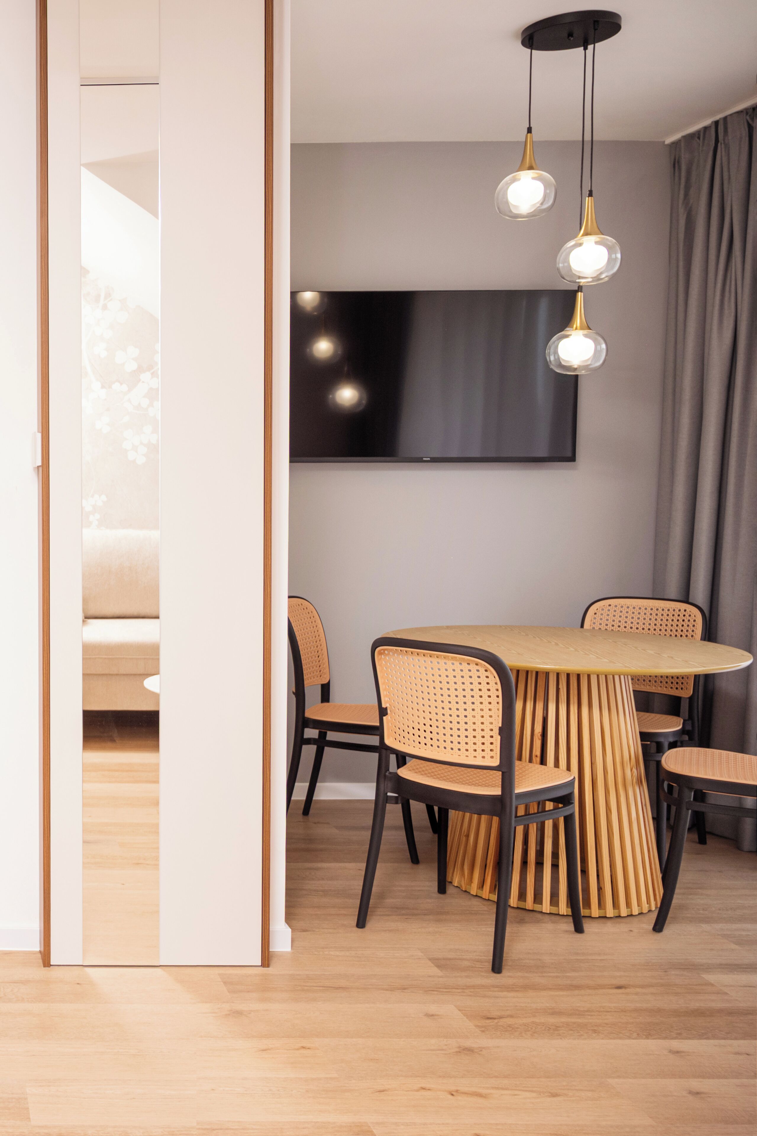 A dining area with a round table, six chairs, and hanging pendant lights.