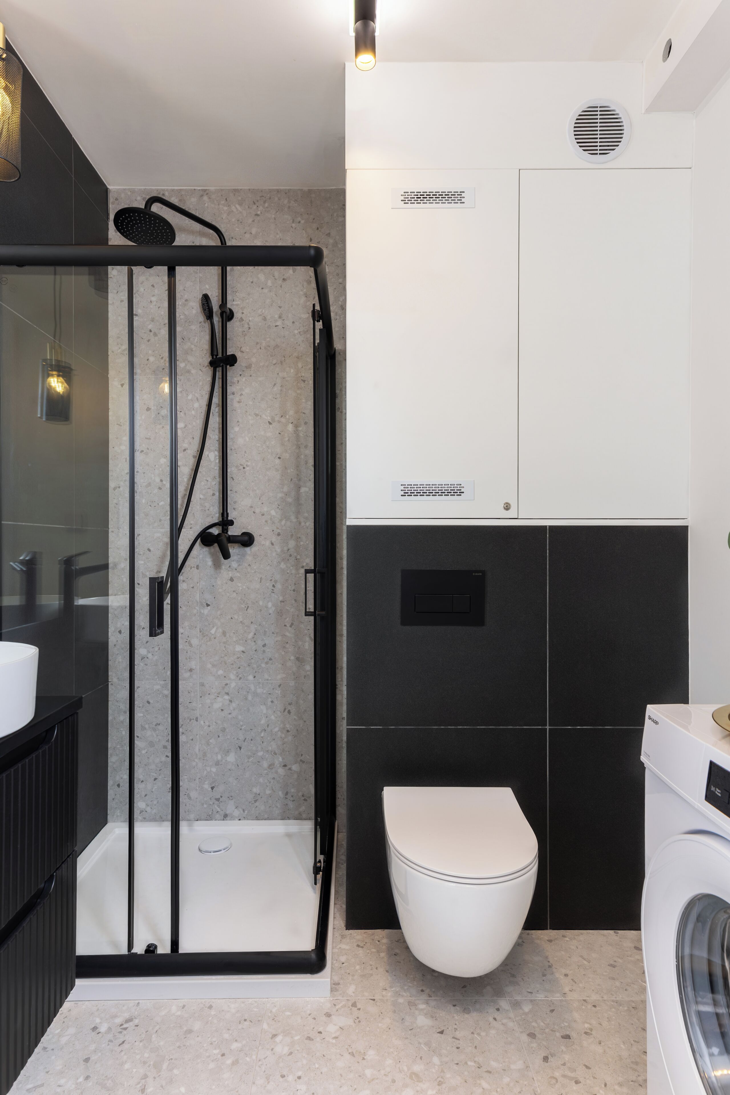Un baño moderno con ducha de vidrio, inodoro blanco y lavadora.