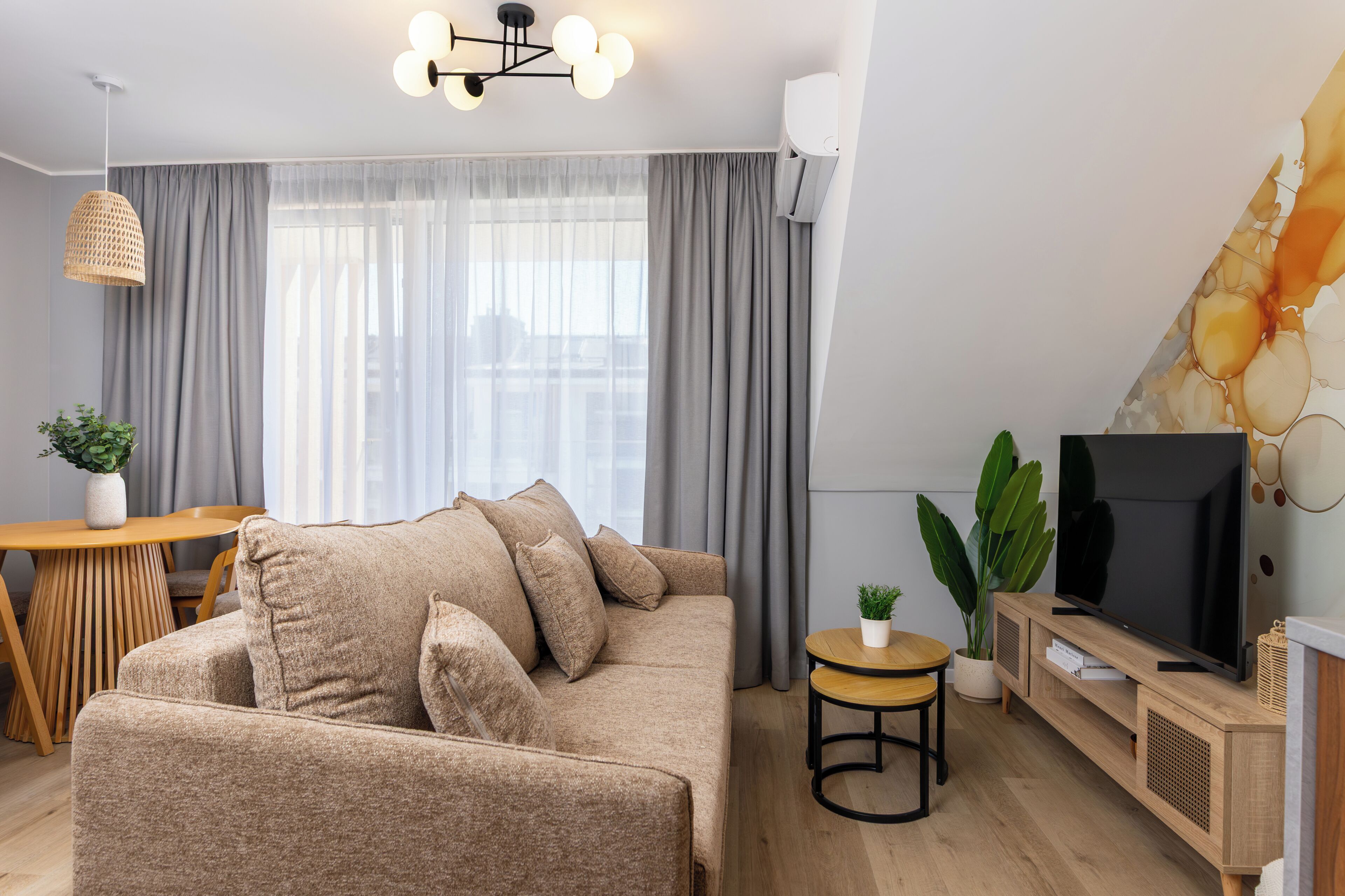 Una sala de estar moderna con un sofá, televisión y comedor.