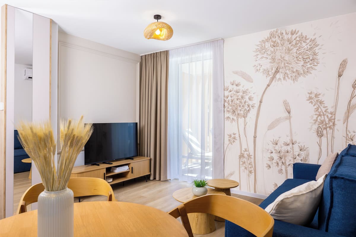Ein modernes Wohnzimmer mit Fernseher, Esstisch und Sofa.