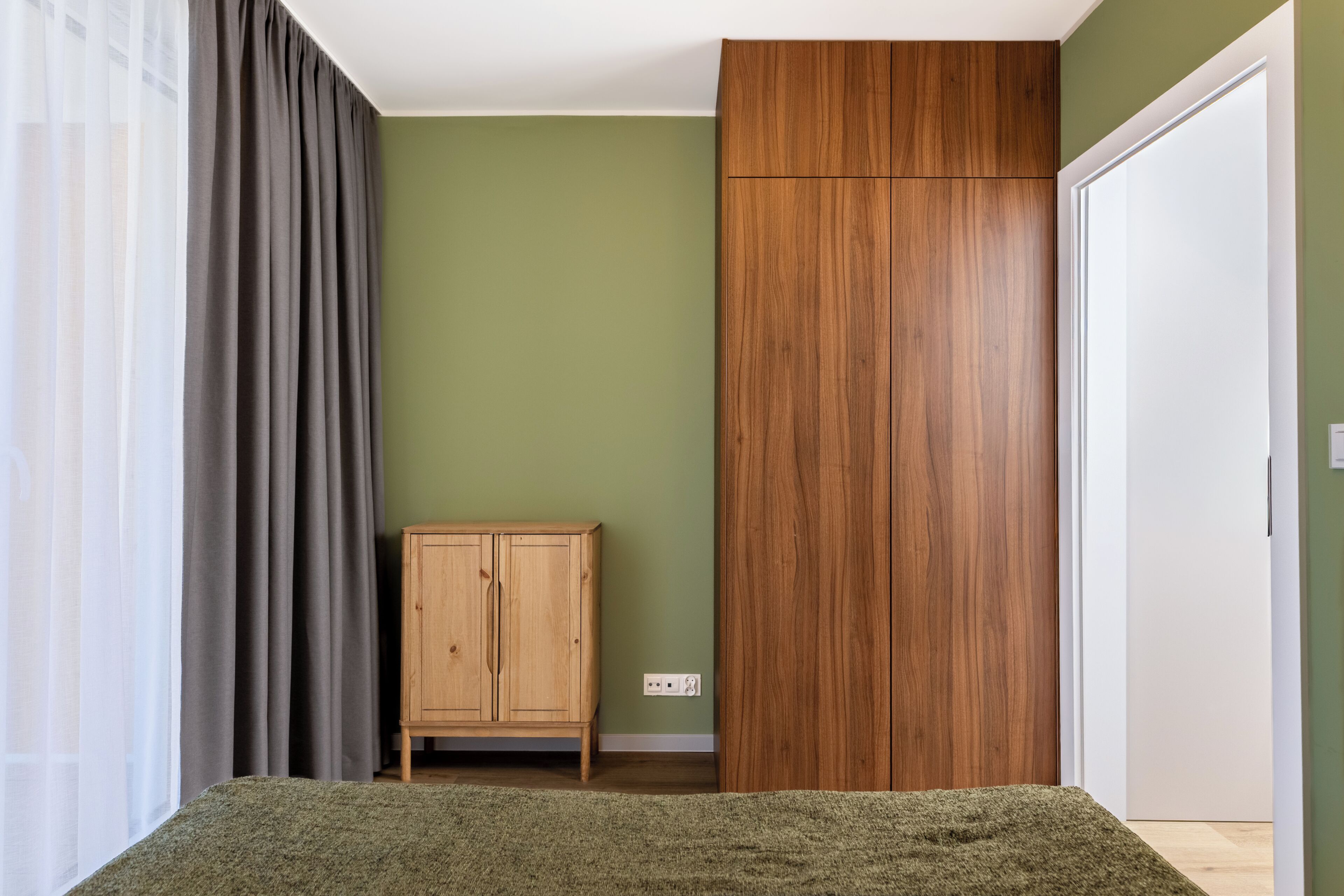 Una habitación con una cama, un armario de madera, un mueble y una puerta.
