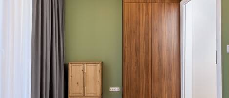 Una habitación con una cama, un armario de madera, un mueble y una puerta.