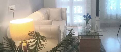 A living room with a sofa, a lamp, a coffee table, and a plant.