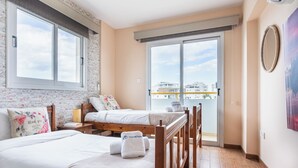Une chambre d’hôtel avec deux lits, un balcon donnant sur des immeubles et une grande fenêtre.