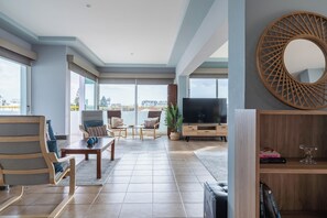 A spacious living area with a large TV, comfortable seating, and a view of the city. - Melograno 2-BR Apt. & Terrace in Larnaca (Larnaca)