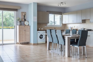 A modern kitchen with a dining area, a washing machine, and a large window.