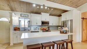 Una cocina moderna con armarios blancos, electrodomésticos de acero inoxidable y una isla grande con taburetes de bar.