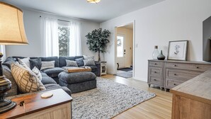 Un salon moderne avec un canapé gris, une table basse en bois et une grande plante.