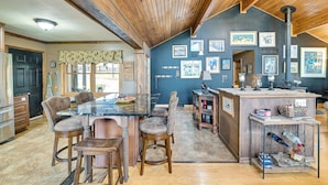 Une cuisine avec un plafond en bois, un plan de travail en marbre et un coin repas avec quatre chaises.
