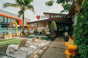 A cafe with outdoor seating, a heart-shaped balloon, and a mascot statue. - Love Rawai Hotel (Rawai)