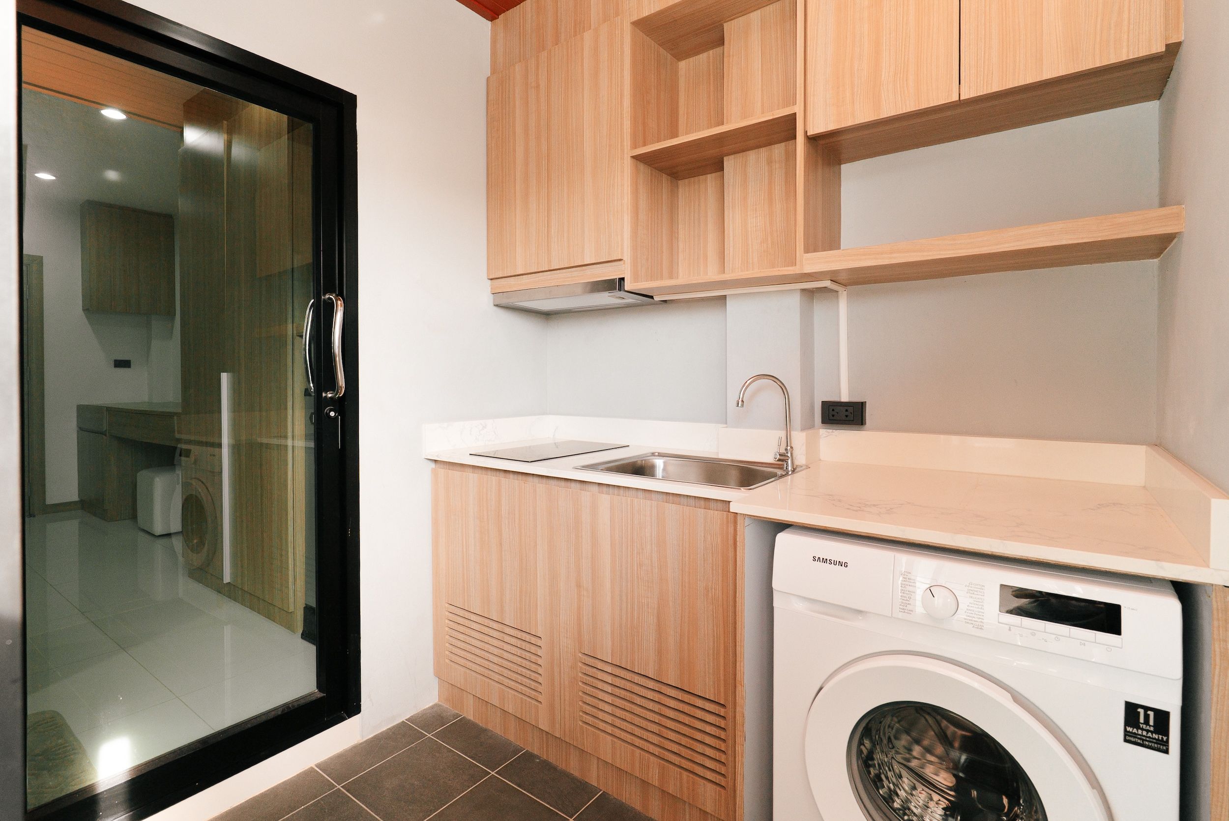 Una cocina compacta con lavadora integrada, un lavamanos y armarios de madera.
