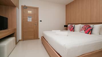 Ein Hotelzimmer mit einem Holzschrank, einem Bett mit weißer Bettwäsche, einem Fernseher auf einem Holztisch und einem Nachttisch.