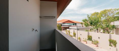 A narrow balcony with a wooden ceiling, a small window, and a wall-mounted faucet.