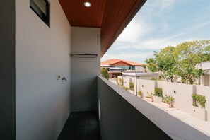 Un balcon étroit doté d’un plafond en bois, d’une petite fenêtre et d’un robinet fixé au mur.