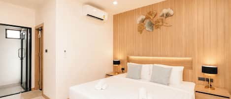 Habitación de hotel con una cama grande, paneles de madera en las paredes, una entrada con puerta de vidrio y un aire acondicionado instalado en la pared.