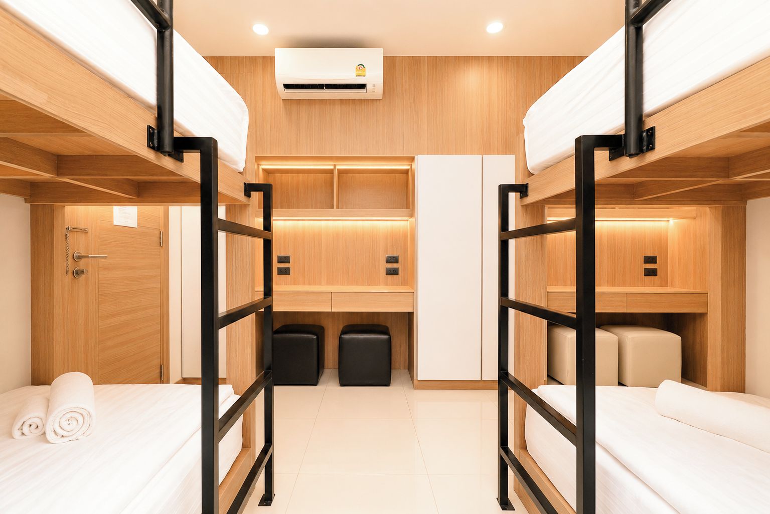 A bunk room with two beds, a small seating area, and a kitchenette.