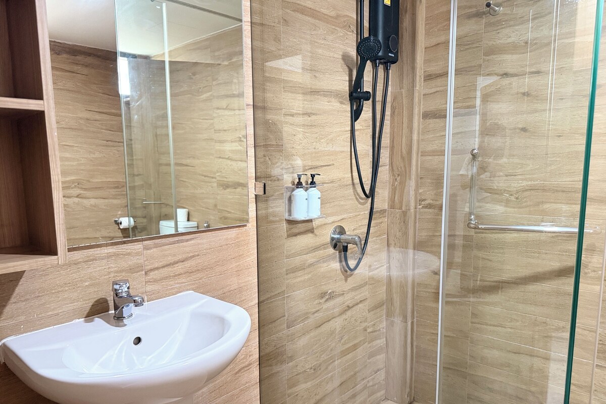 Ein Badezimmer mit einem weißen Waschbecken, einer Duschkabine aus Glas und einem Spiegel.