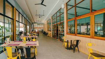A spacious indoor dining area with high ceilings, large windows, and modern furniture.