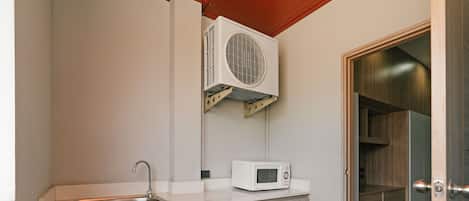 Cozinha compacta com pia embutida, micro-ondas e ar-condicionado fixado na parede.
