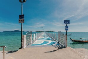 Un molo che si estende su un corpo d'acqua sotto un cielo sereno, con un'imbarcazione ormeggiata a destra e segnali indicatori.