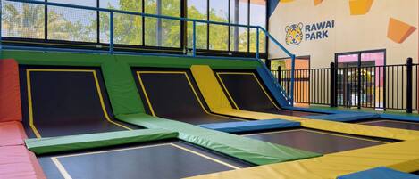 An indoor trampoline area with safety railings and a wall with the text 'RAWAI PARK'.