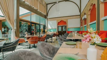 Un restaurante con techos altos, muebles modernos y vista a la calle.