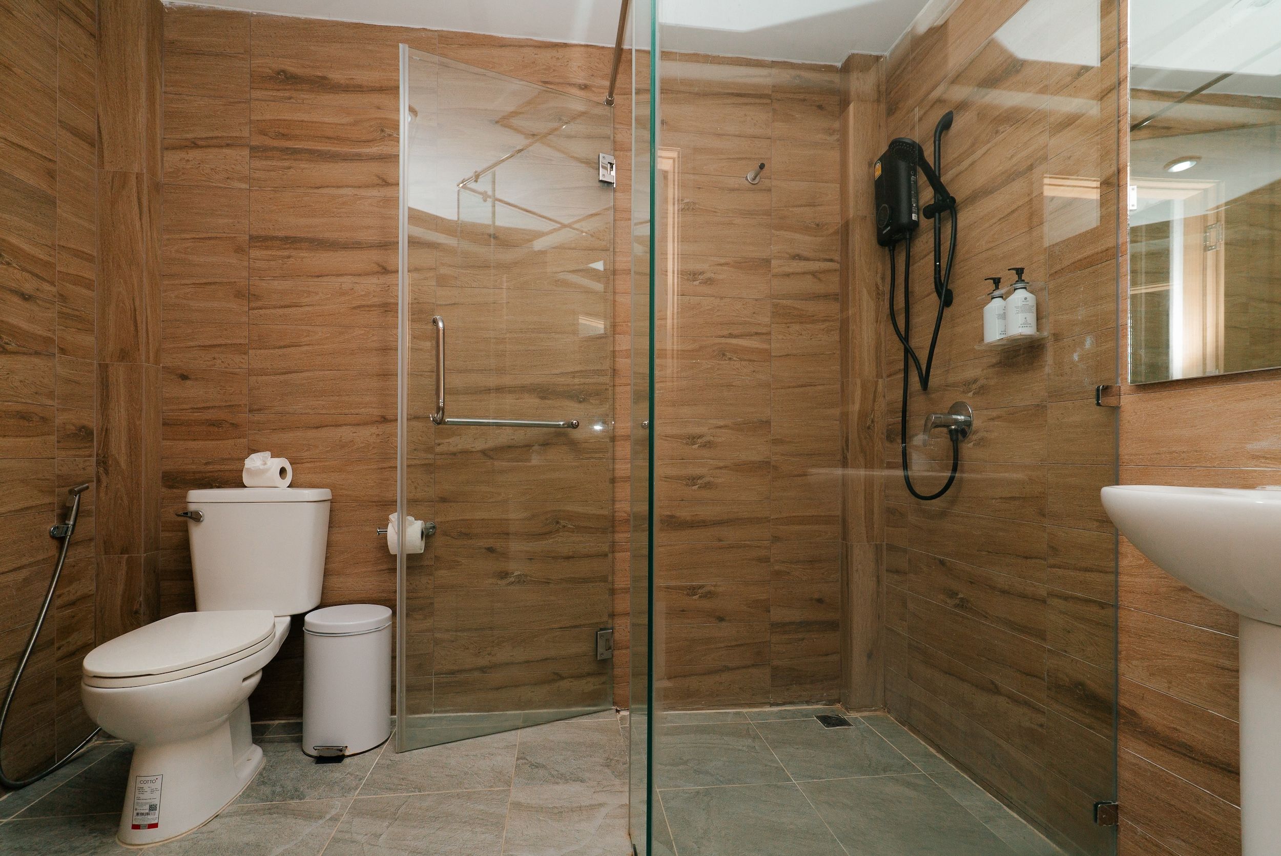 A bathroom with a glass shower enclosure, a toilet, a bidet, and a sink.