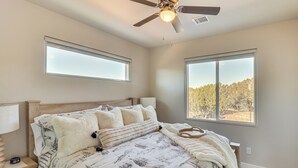 A bedroom with a bed, two windows, a ceiling fan, and a nightstand with a lamp. - Show Low Home w/ Deck: Near Lake & Trails! (Show Low)