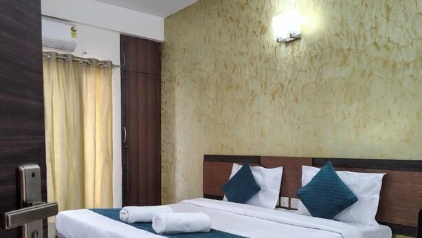 Een netjes opgemaakt bed met wit en teal beddengoed, een houten hoofdbord en een gestructureerde wand erachter.