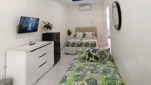 Une chambre à coucher avec un lit, une télévision, un bureau et une commode.