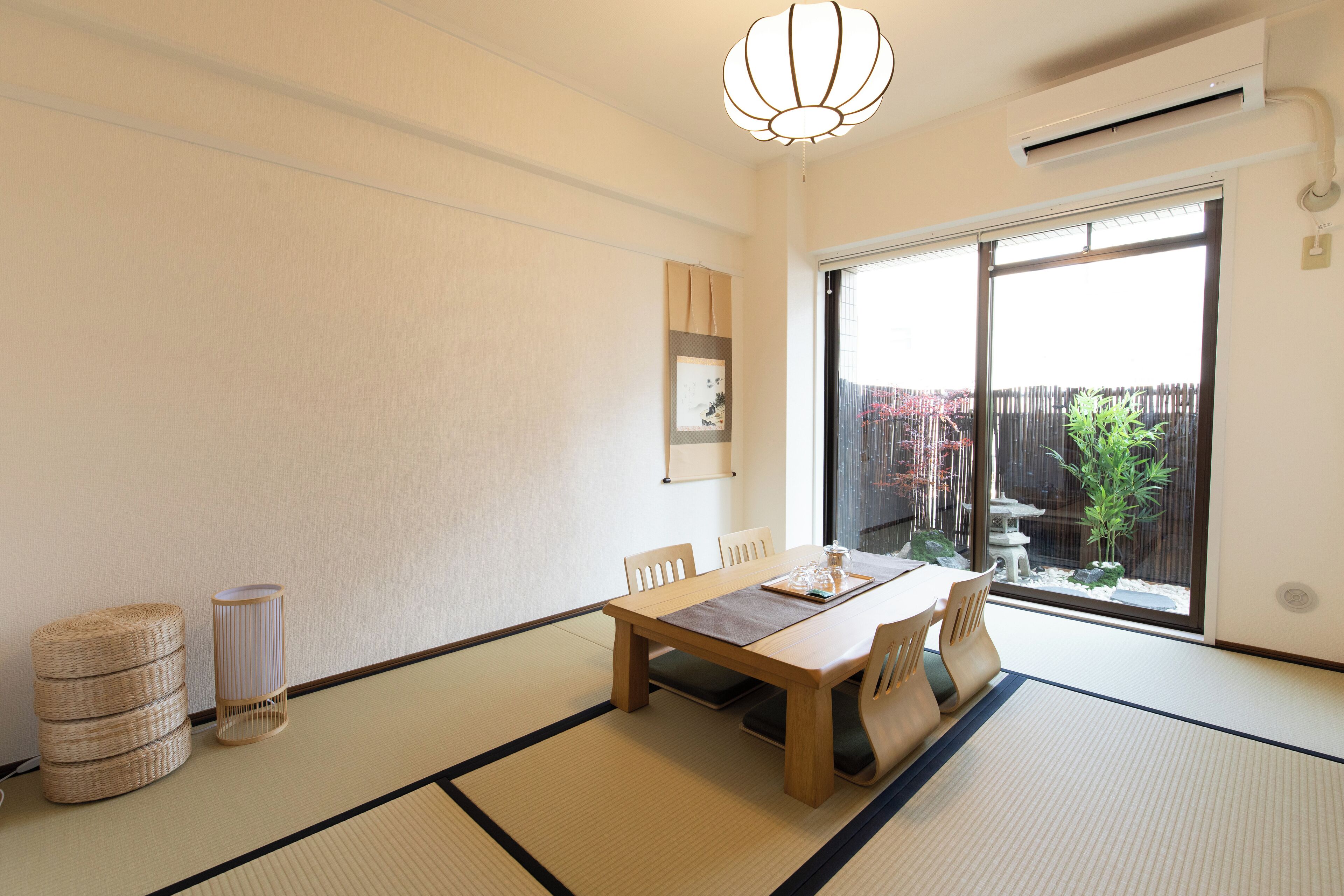 A traditional Japanese-style room with tatami flooring, a low wooden table, and a sliding glass door leading to a garden.
