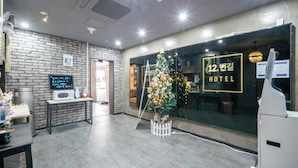 A hotel reception area with a brick wall, a Christmas tree, a reception desk, and a sign reading '12. 반길 HOTEL'. - Cheongju 12beon-gil  (Cheongju)