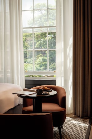 A hotel room with a large window, a bed, a table with a croissant, and a chair. - The Kithmore Hotel (St. Andrews)