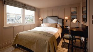 Ein Schlafzimmer mit einem Bett, Nachttischlampen, einem Schreibtisch und einem Stuhl.