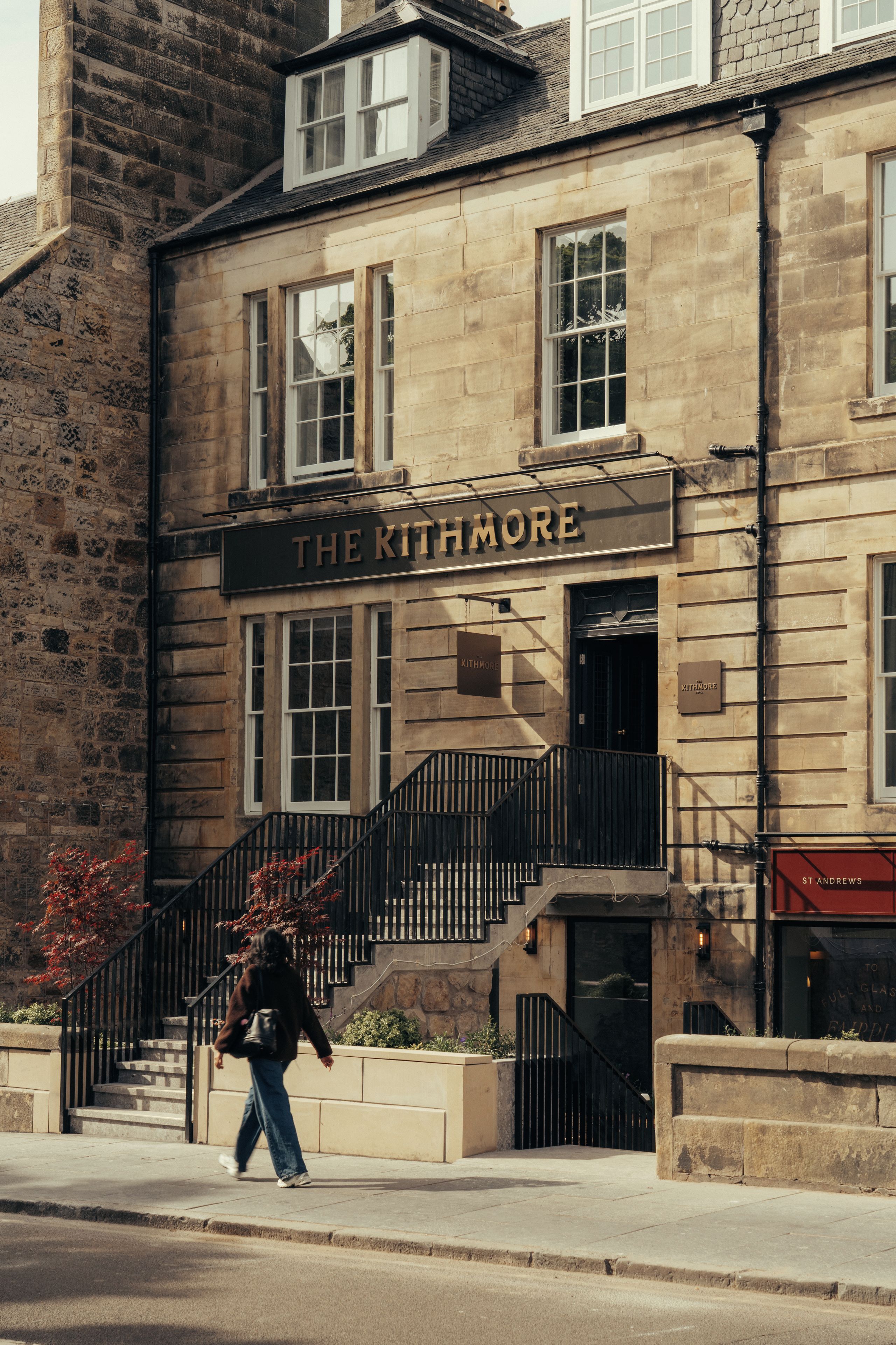 A stone building with a sign reading 'The Kithmore' and a staircase leading to the entrance.