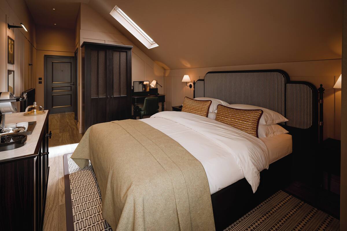 A hotel room with a bed, desk, chair, and a wardrobe.