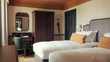 A hotel room with two beds, a desk, a chair, a wardrobe, and a mirror.