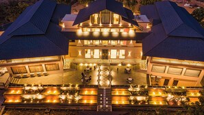 A multi-story hotel with a central courtyard, outdoor seating, and a well-lit entrance. - Amruthan Bagh Resort  (Udaipur)