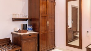 A wooden wardrobe with two doors, a mirror, and a shelf with jars and bottles. - Amruthan Bagh Resort  (Udaipur)