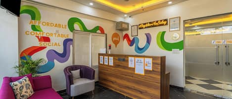 A reception area with a wooden desk, a purple sofa, and a reception desk with informational posters.