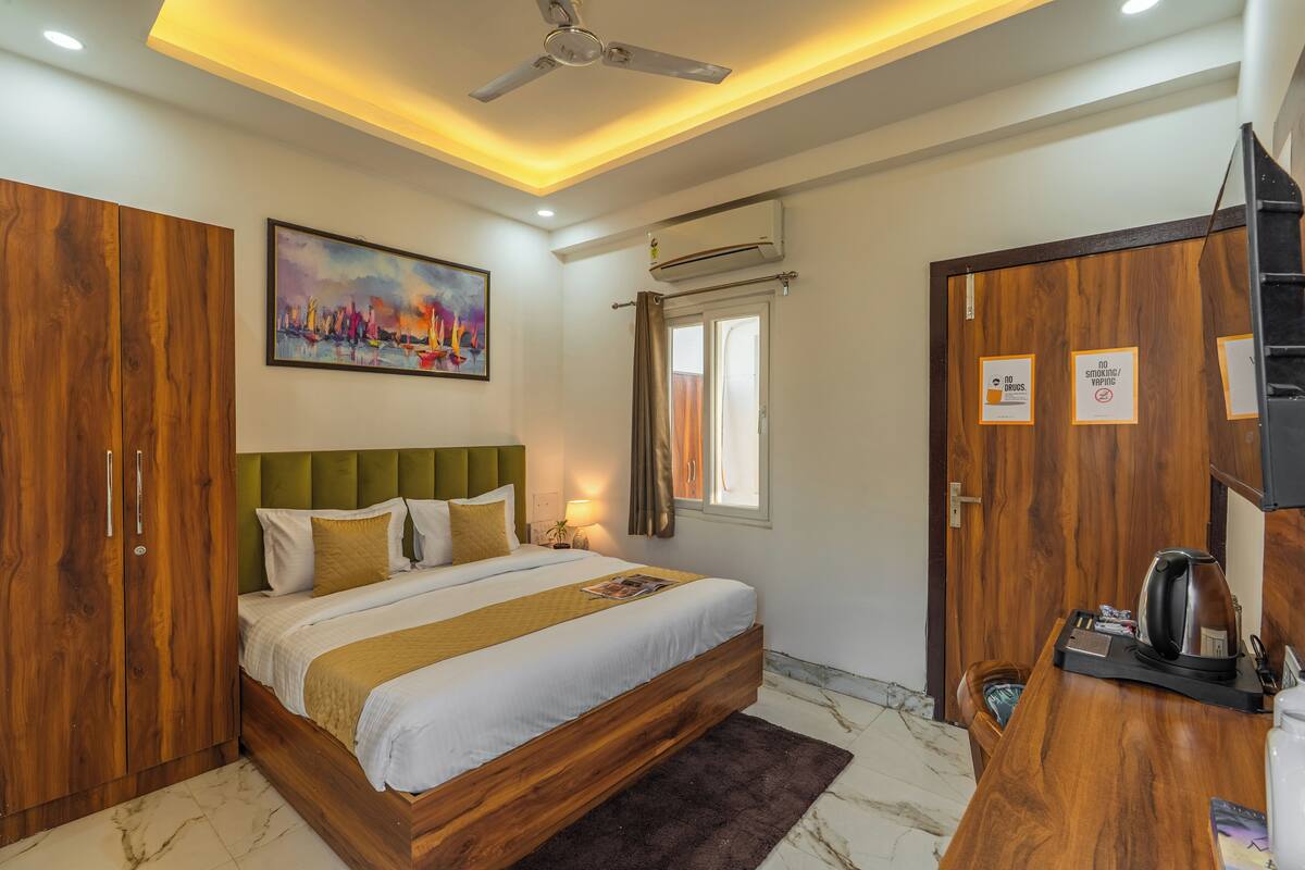 Quarto de hotel com cama, guarda-roupa, escrivaninha e obras de arte.