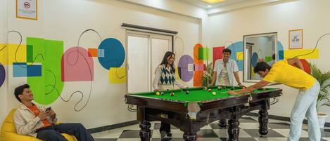 A pool table in a room with a checkered floor, a 'KEEP IT CLEAN' sign, and abstract wall art.