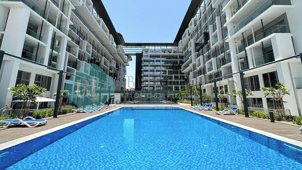 Een modern hotel met een centraal gelegen zwembad, meerdere balkons en een heldere lucht.
