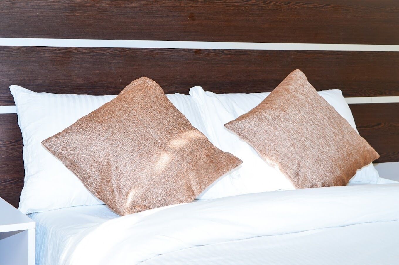 Una cama con dos almohadas y un cabecero de madera.