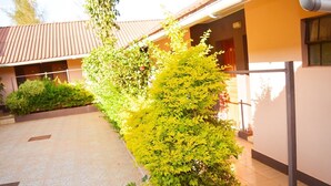 A building with a tiled patio and a well-maintained hedge. - Mzedu Springs Hotel Mwatate (Taita Hills)