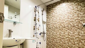 Un bagno con doccia, lavandino e specchio.