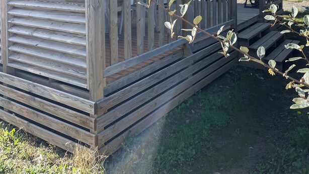 A small wooden cabin with a covered porch and a visible door. - Mobile home with terrace and heated pool in the heart of the seaside resort (Port-la-Nouvelle)