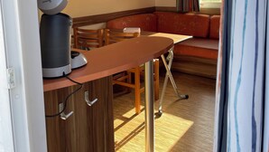 A compact living space with a kitchenette, a dining area, and a seating area with a sofa. - Mobile home with terrace and heated pool in the heart of the seaside resort (Port-la-Nouvelle)