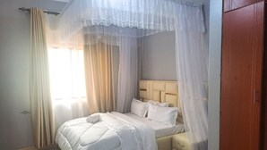 Ein ordentlich bezogenes Bett mit Baldachin, ein Nachttisch und ein Kleiderschrank.