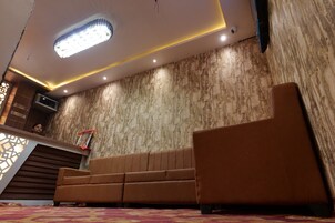 Un área de recepción con diseño moderno, que incluye un sofá, un muro con diseño y una lámpara de araña.